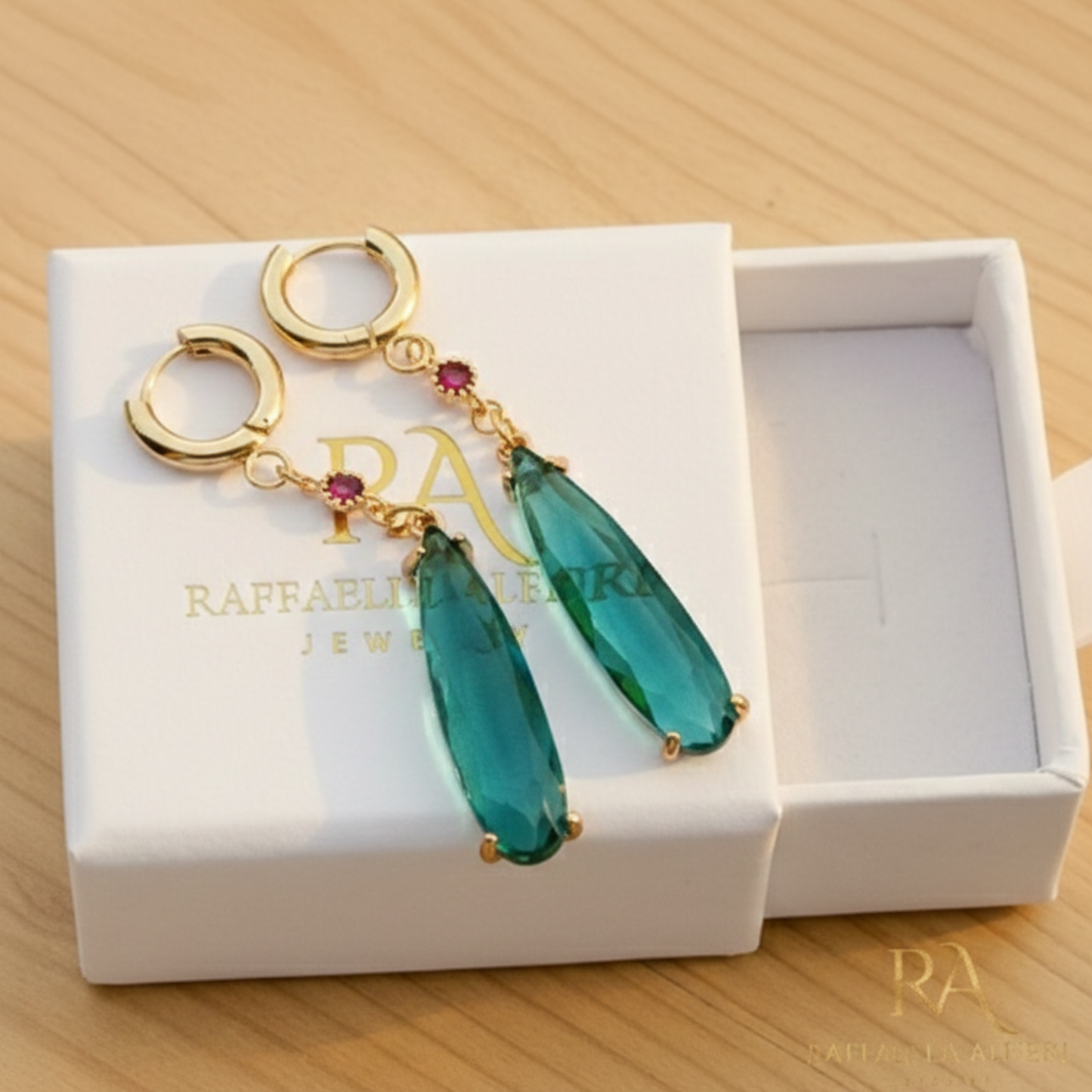 Coppia di orecchini a cerchio dorati con goccia pendente verde smeraldo e piccolo cristallo rosso, ispirati al personaggio Howl de Il Castello Errante di Howl, gioielli cosplay eleganti.